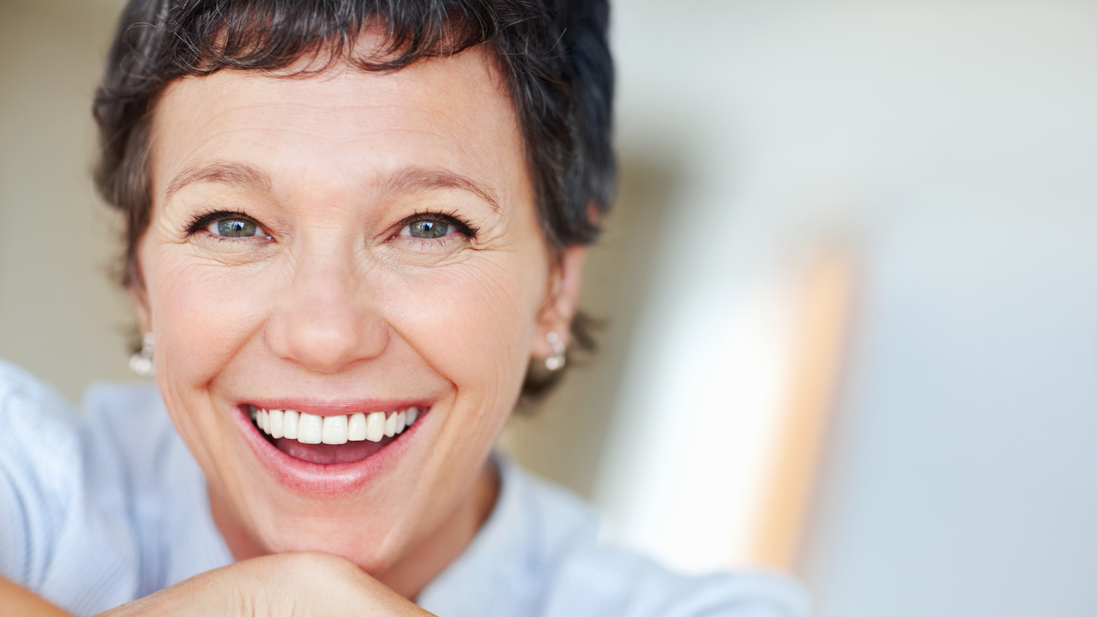 A bright-eyed woman smiles at the camera