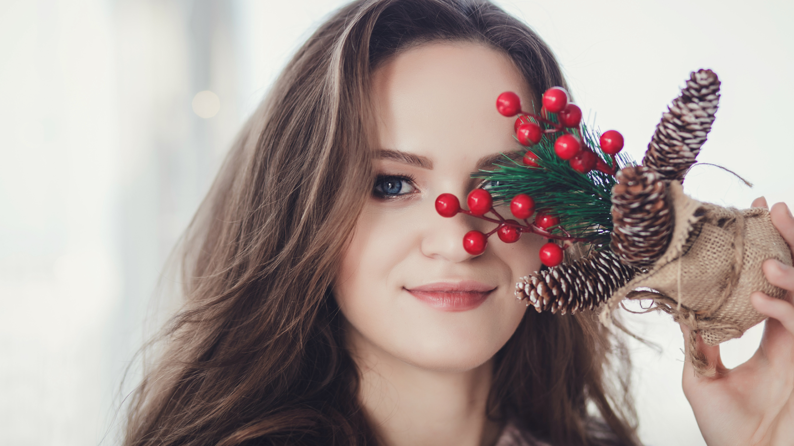 A woman holds a bundle of holiday decorations in front of her smooth face