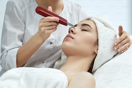 A clinician wields a device on a woman laying down during a microdermabrasion.