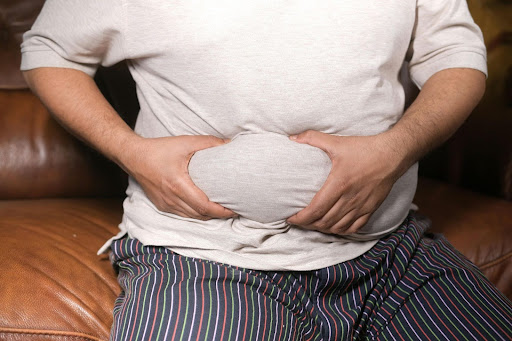 Man in white shirt and striped pants, grabbing his belly.