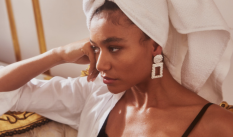 A young woman with a towel wrapped around her head poses with some cleavage exposed.